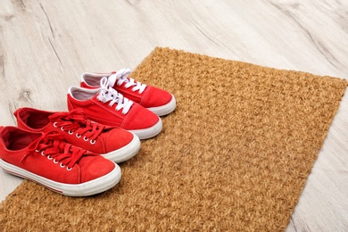 Photo of New clean doormat with shoes on floor. Space for text