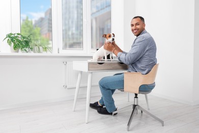 Young man with Jack Russell Terrier at desk in home office