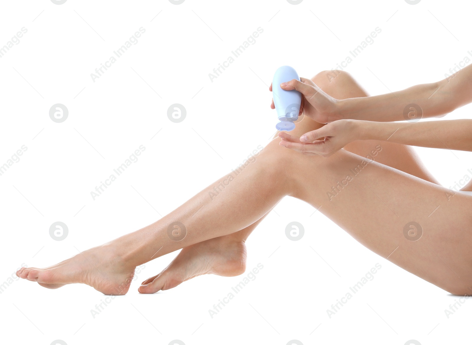 Photo of Young woman applying cream onto her legs on white background, closeup