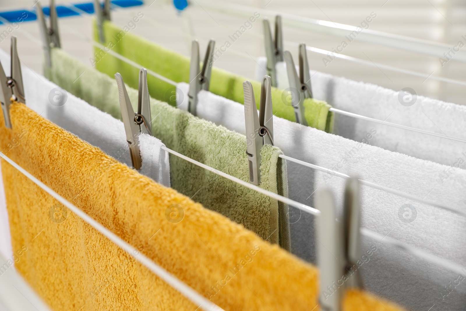 Photo of Clean terry towels hanging on drying rack, closeup