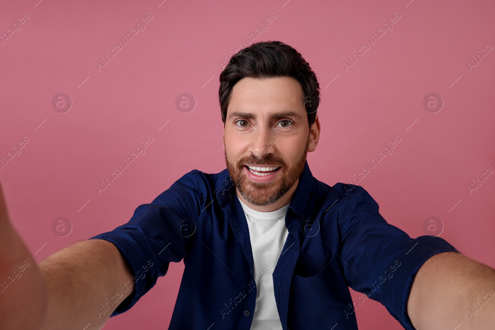 Photo of Smiling man taking selfie on pink background
