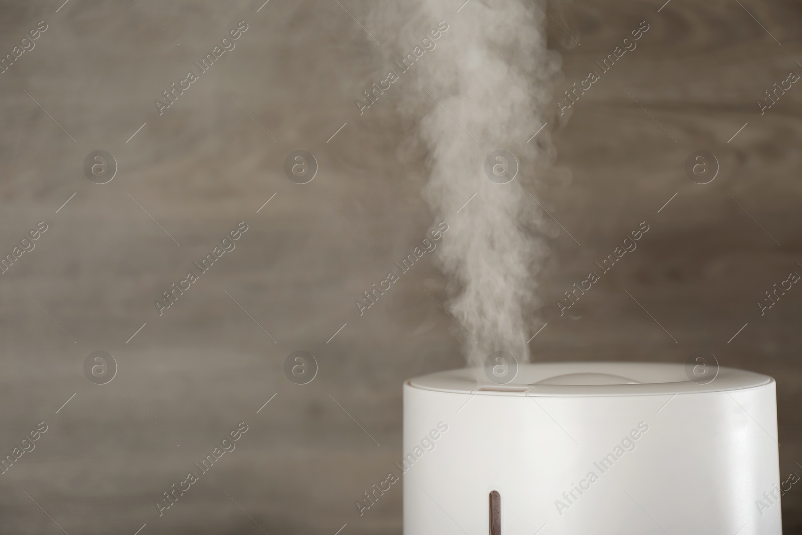 Photo of Modern air humidifier on wooden background, closeup. Space for text