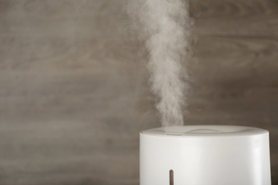Photo of Modern air humidifier on wooden background, closeup. Space for text