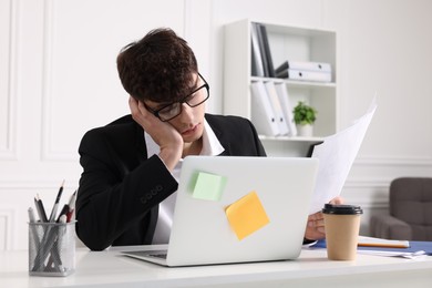 Photo of Tired young man working at table in office. Deadline concept