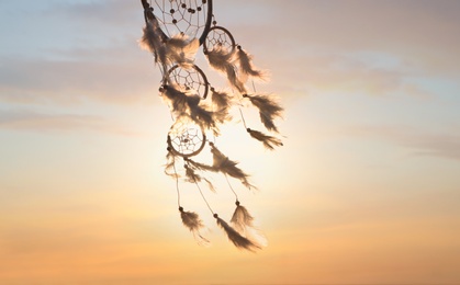 Photo of Handmade dream catcher against beautiful sunset sky. Space for text