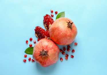 Photo of Ripe pomegranates and leaves on color background, top view