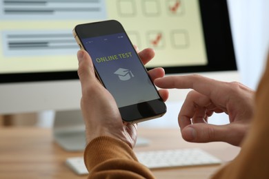 Photo of Man taking online test on smartphone at desk indoors, closeup