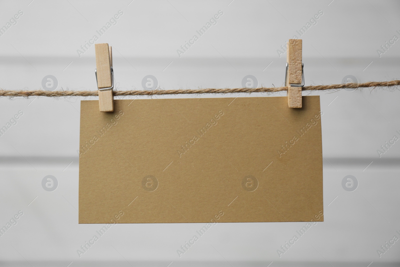Photo of Clothespins with blank notepaper on twine against white wooden background. Space for text