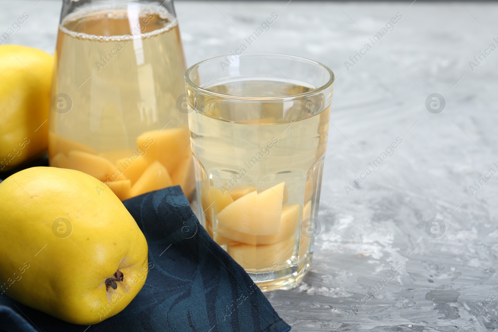 Photo of Delicious quince drink and fresh fruits on grey table, closeup