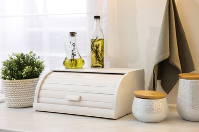 Wooden bread box and decorative elements on white countertop in kitchen