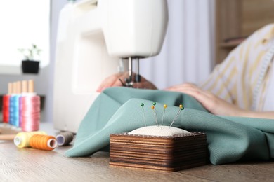 Seamstress working with sewing machine at wooden table indoors, selective focus