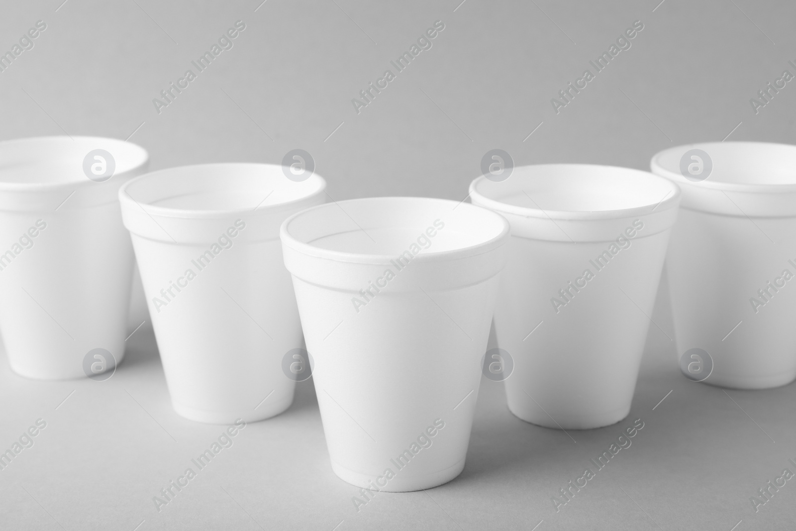 Photo of Styrofoam cups on light grey background, closeup