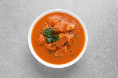 Photo of Bowl of delicious chicken curry on light grey table, top view