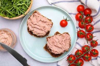 Delicious liverwurst sandwiches, tomatoes and arugula on white table, flat lay