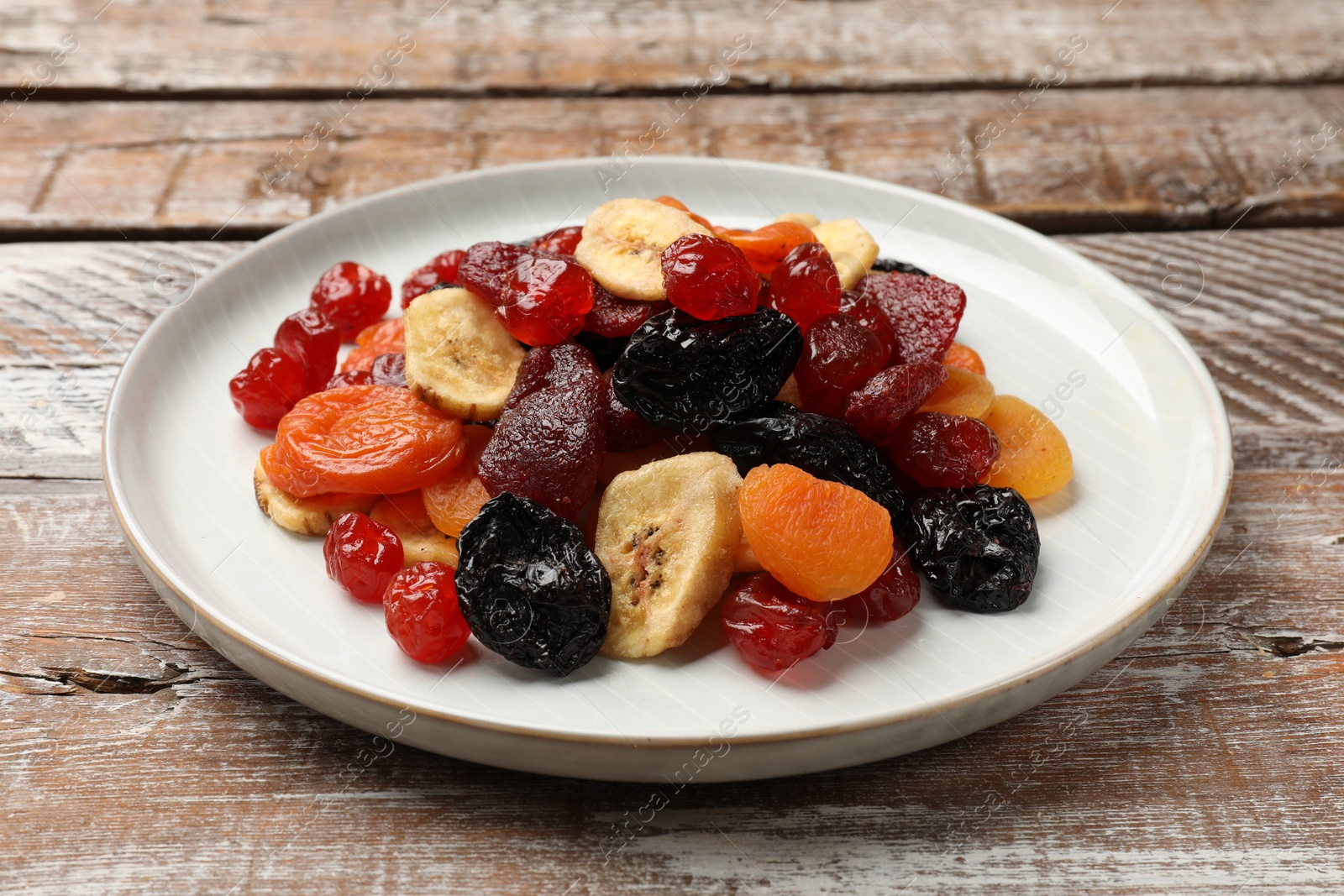 Photo of Mix of delicious dried fruits on wooden table, closeup