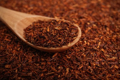 Photo of Wooden spoon on dry rooibos leaves, closeup view