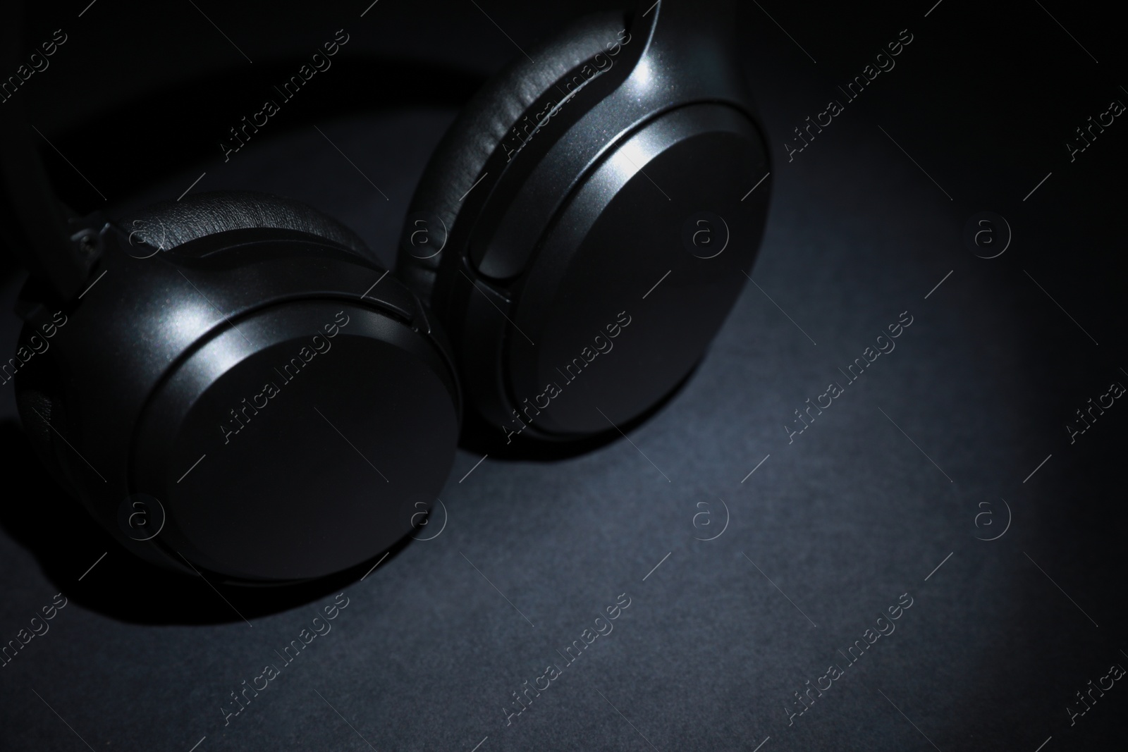 Photo of Modern wireless headphones on dark background, space for text