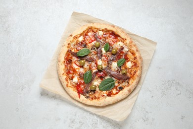 Photo of Tasty pizza with anchovies, basil and olives on white table, top view