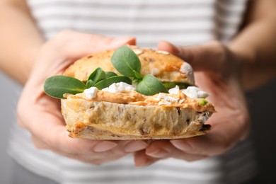 Photo of Woman holding delicious sandwich with hummus and microgreens, closeup