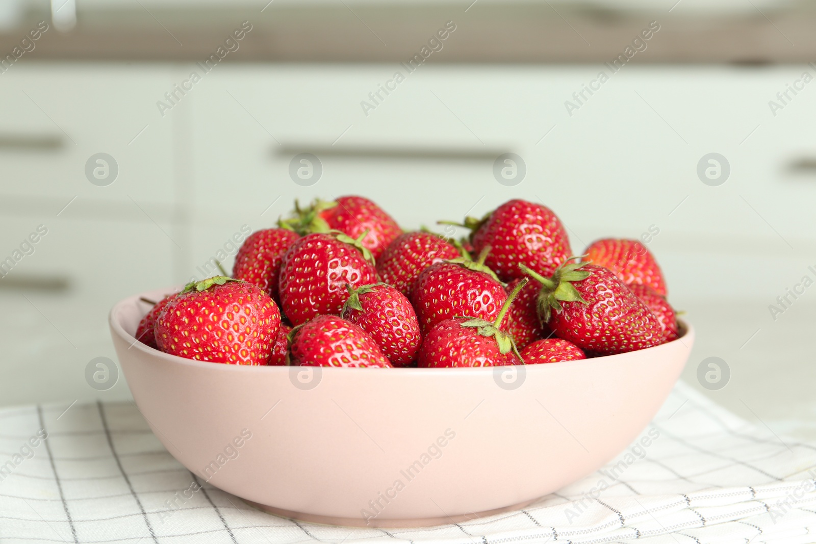 Photo of Delicious ripe strawberries in bowl on table indoors