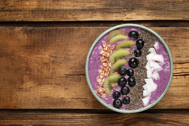 Healthy breakfast with delicious acai smoothie and fruits in bowl on wooden table, top view. Space for text