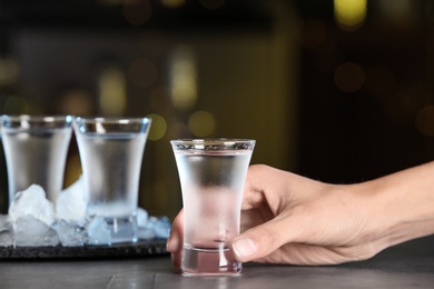 Photo of Woman with shot of vodka at table in bar, closeup