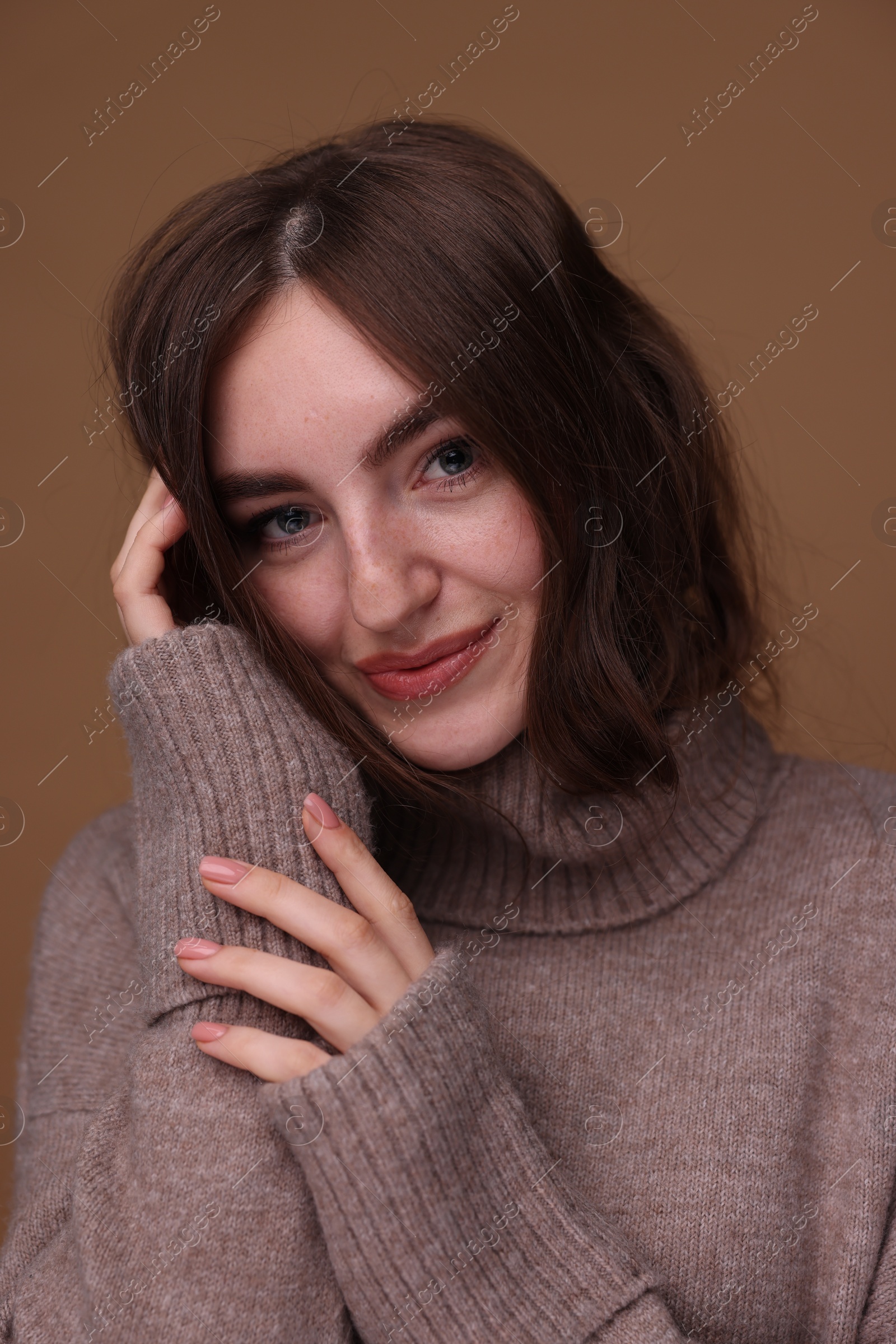 Photo of Portrait of beautiful young woman in warm sweater on brown background