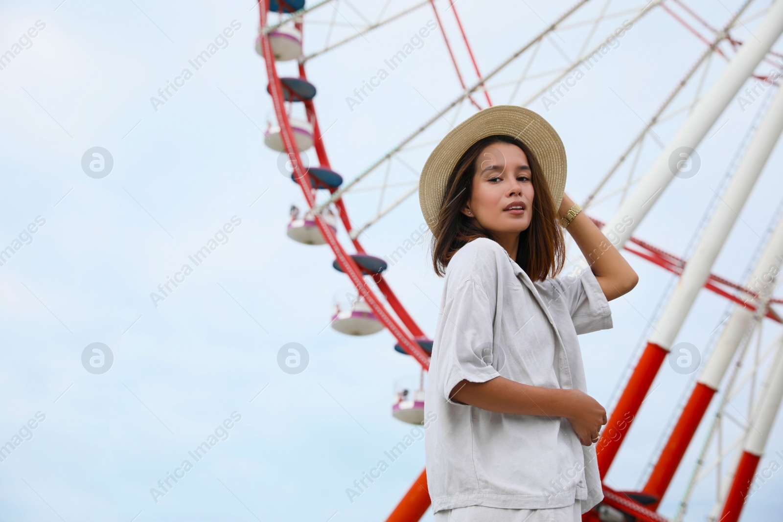 Photo of Beautiful young woman near Ferris wheel outdoors, low angle view