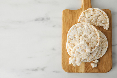 Photo of Puffed rice cakes on white wooden table, top view. Space for text