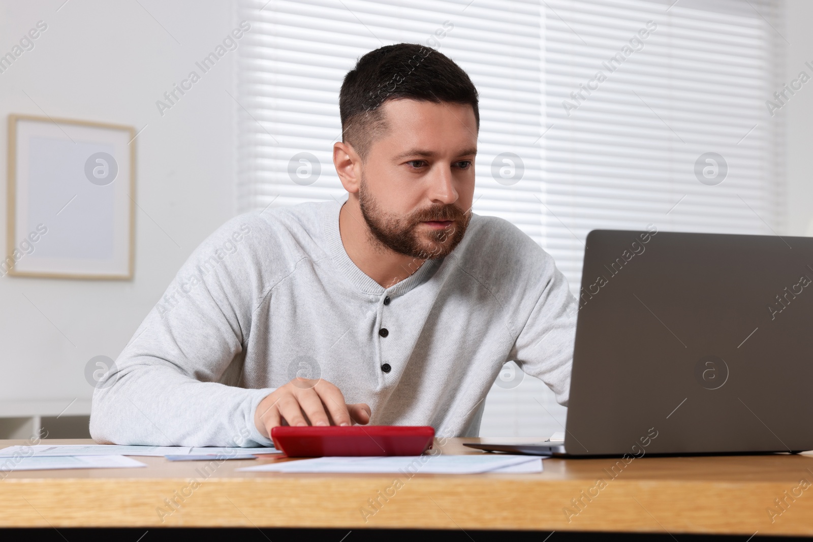 Photo of Man calculating taxes at table in room