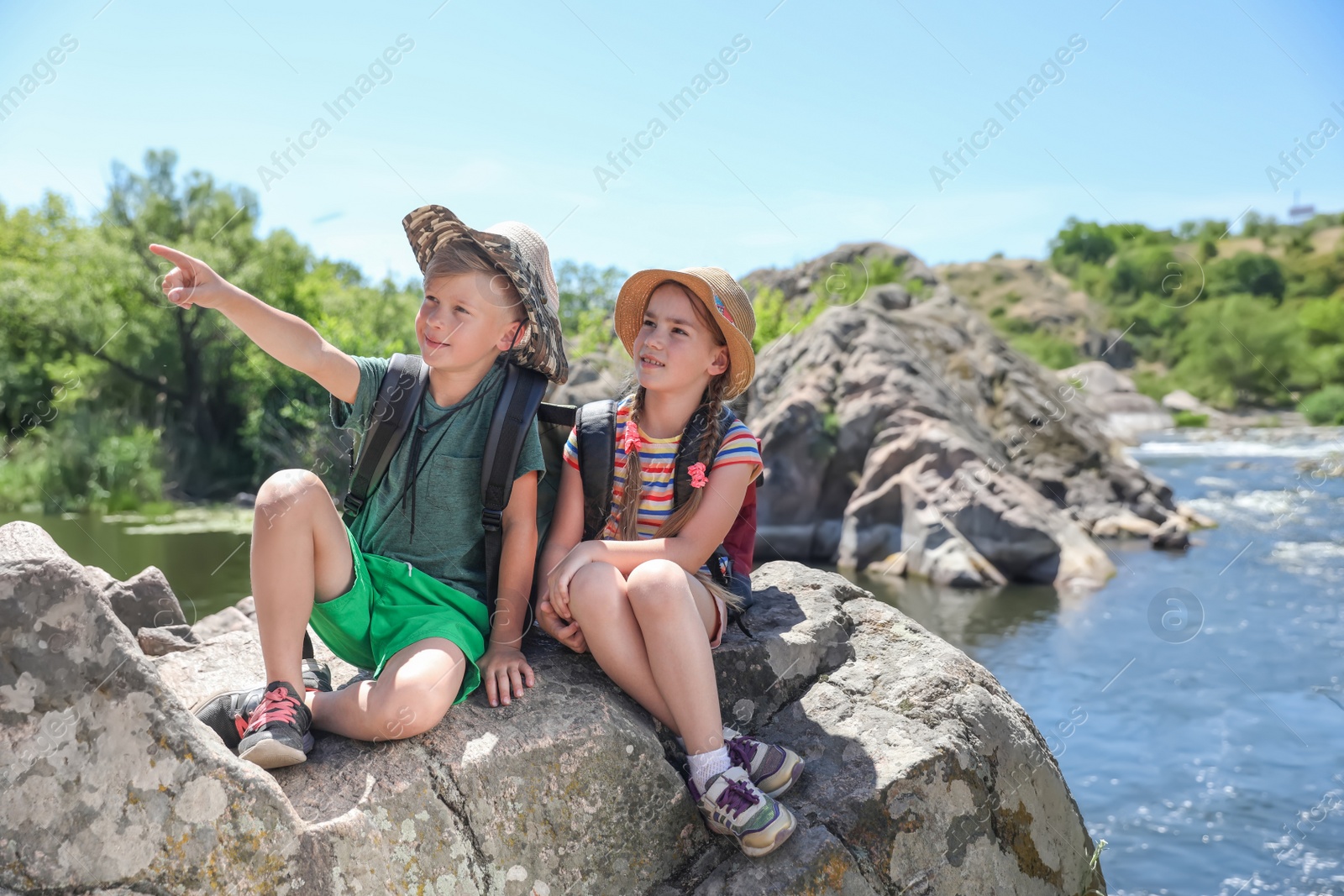 Photo of Little children on rock near river. Summer camp