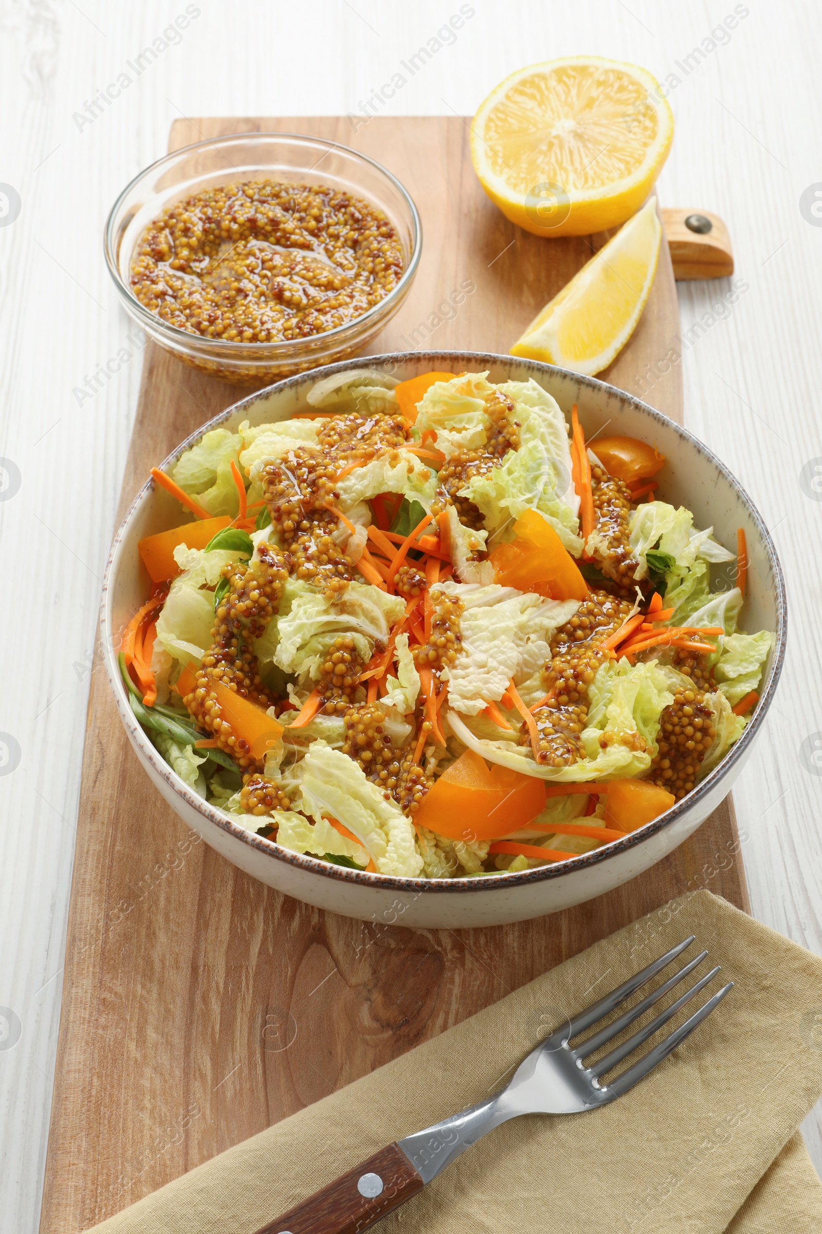 Photo of Delicious salad with Chinese cabbage and mustard seed dressing on white wooden table