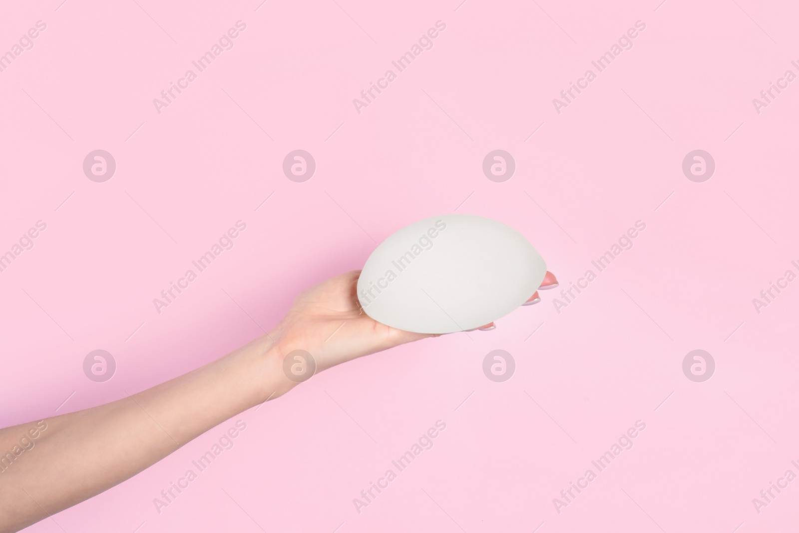 Photo of Woman holding silicone implant for breast augmentation on color background, space for text. Cosmetic surgery