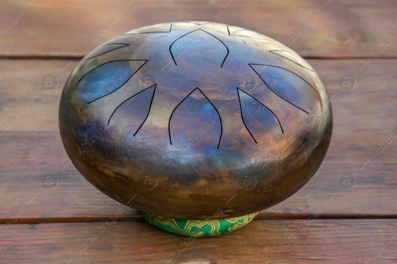 Photo of Steel tongue drum on wooden table. Percussion musical instrument