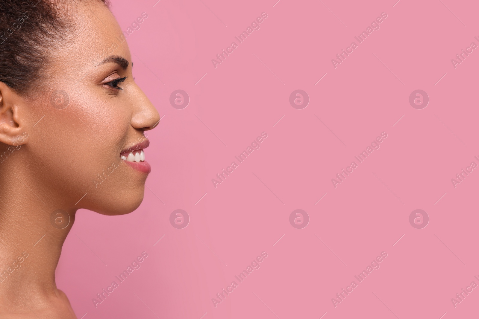 Photo of Beautiful young woman with glamorous makeup on pink background, closeup. Space for text