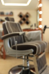 Photo of Blurred view of hairdresser's workplace with professional armchair in barbershop