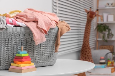 Photo of Laundry basket with baby clothes on white table in room. Space for text