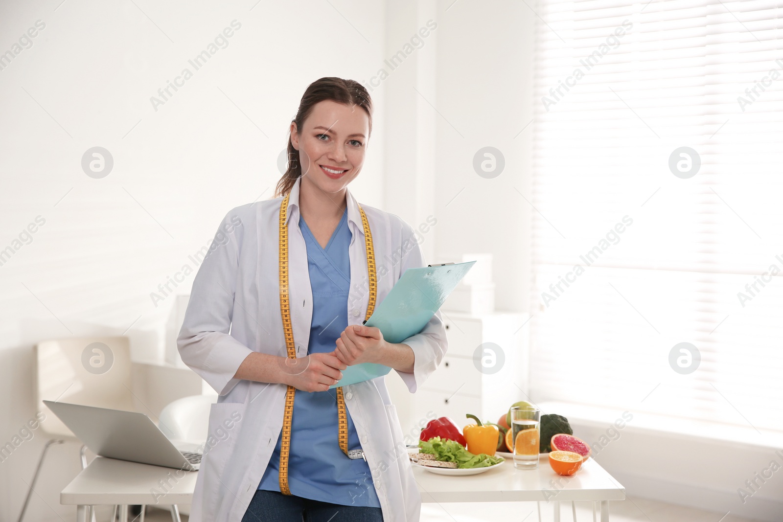 Photo of Nutritionist with measuring tape and clipboard in office. Space for text