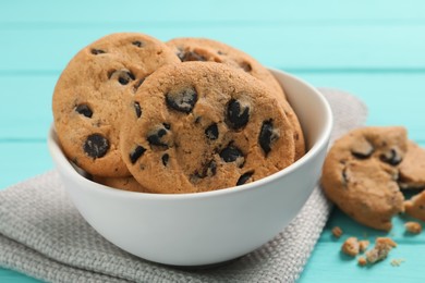 Photo of Bowl with many delicious chocolate chip cookies on turquoise table, closeup