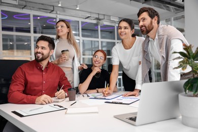 Photo of Team of employees working together in office