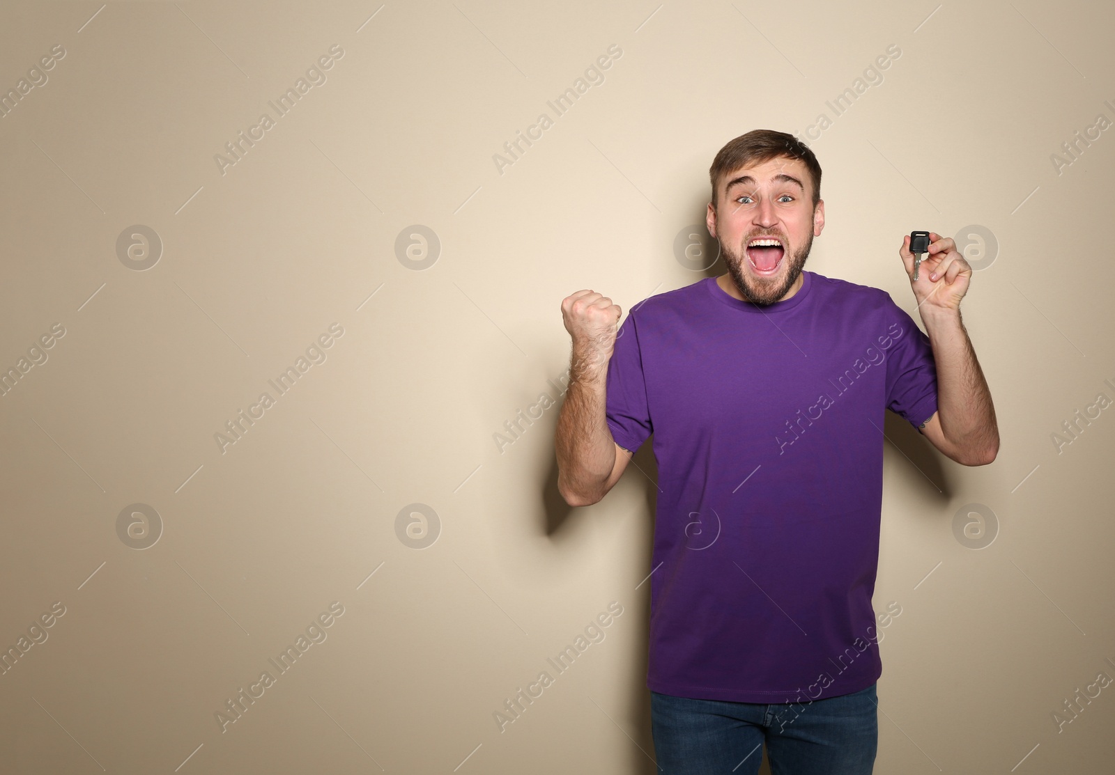 Photo of Happy young man with car key on color background, space for text. Getting driving license