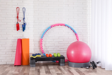 Different sports equipment near white brick wall in gym