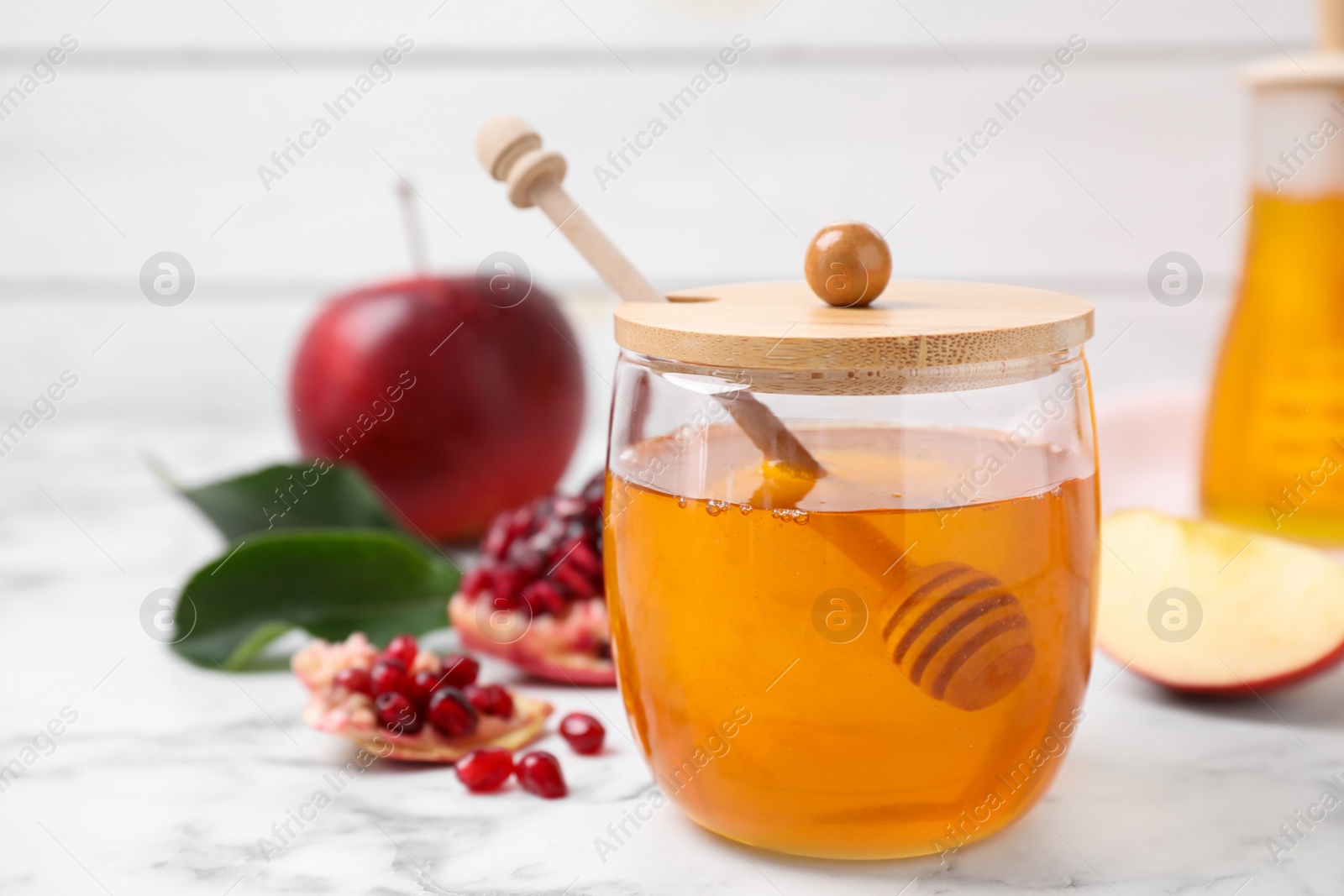 Photo of Honey, apples and pomegranate on white marble table. Rosh Hashanah holiday