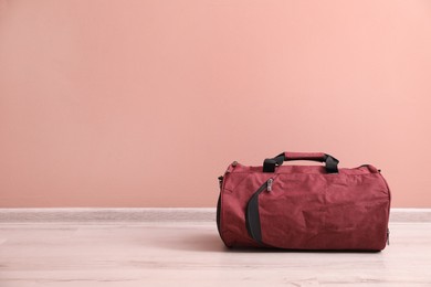 Photo of Red sports bag on floor near pink wall, space for text