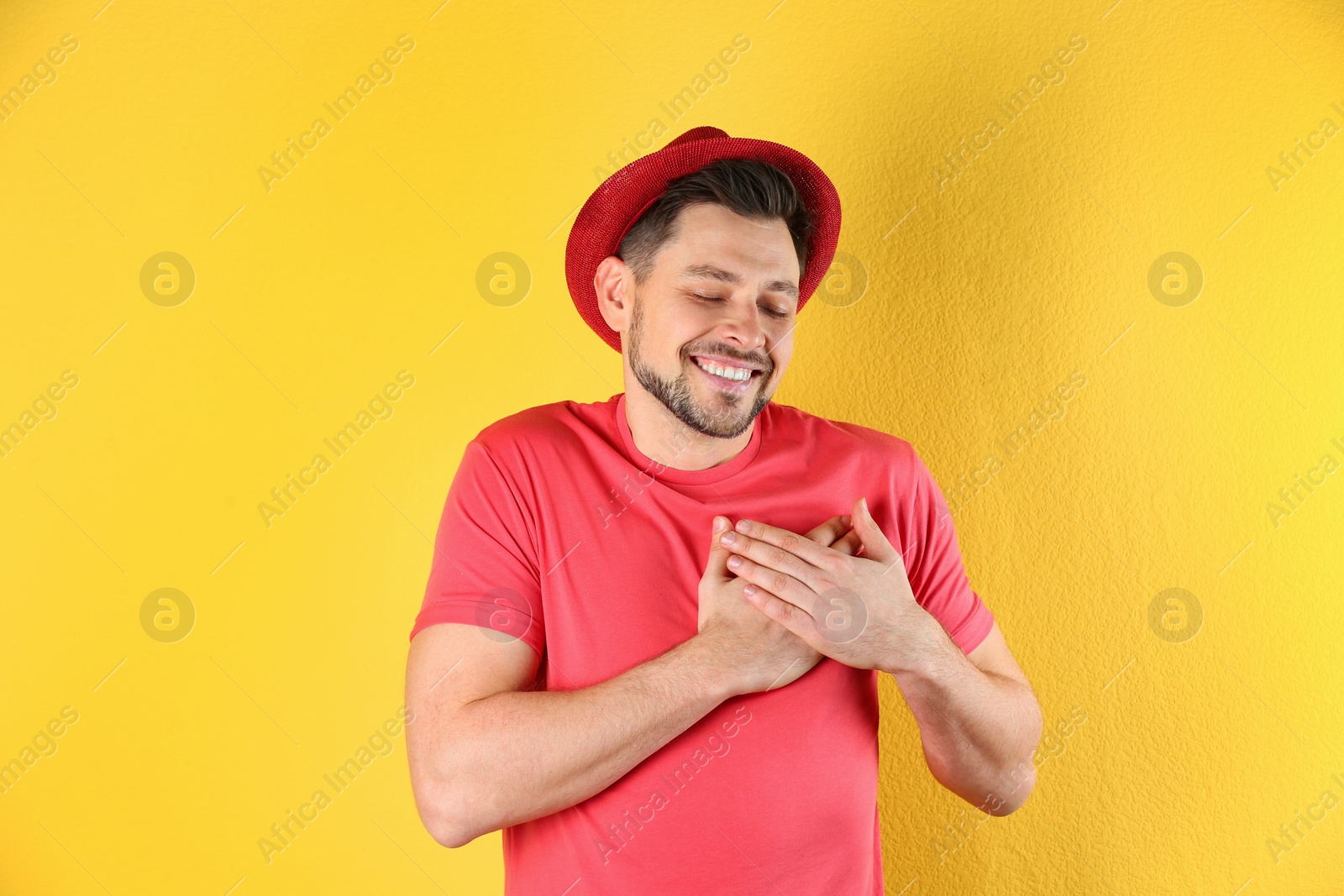 Photo of Portrait of handsome man holding hands near his heart on color background