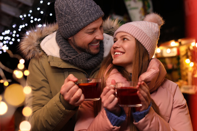 Happy couple with mulled wine at winter fair