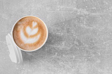 Coffee to go. Paper cup with tasty drink on grey table, top view. Space for text