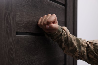 Photo of Military commissariat representative knocking on wooden door, closeup