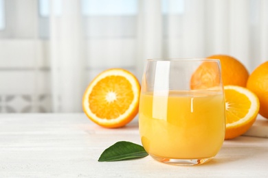 Photo of Glass with orange juice and fresh fruit on table, space for text