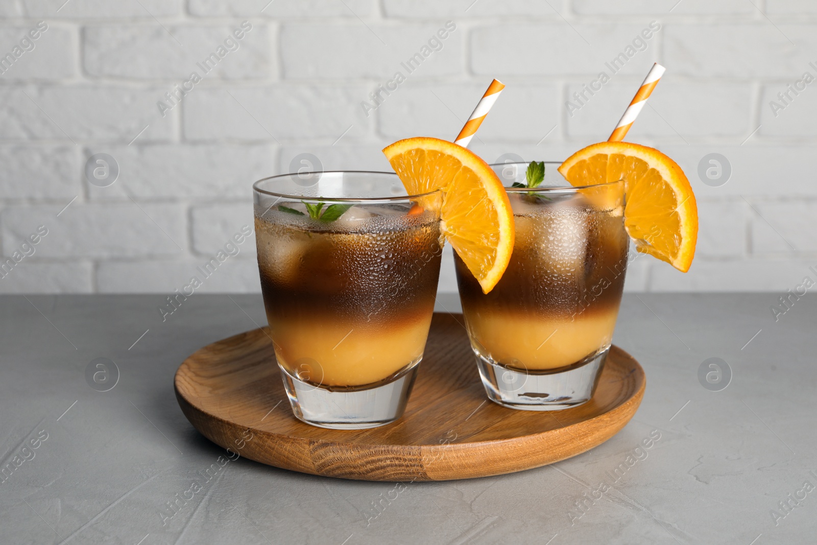 Photo of Tasty refreshing drink with coffee and orange juice on grey table